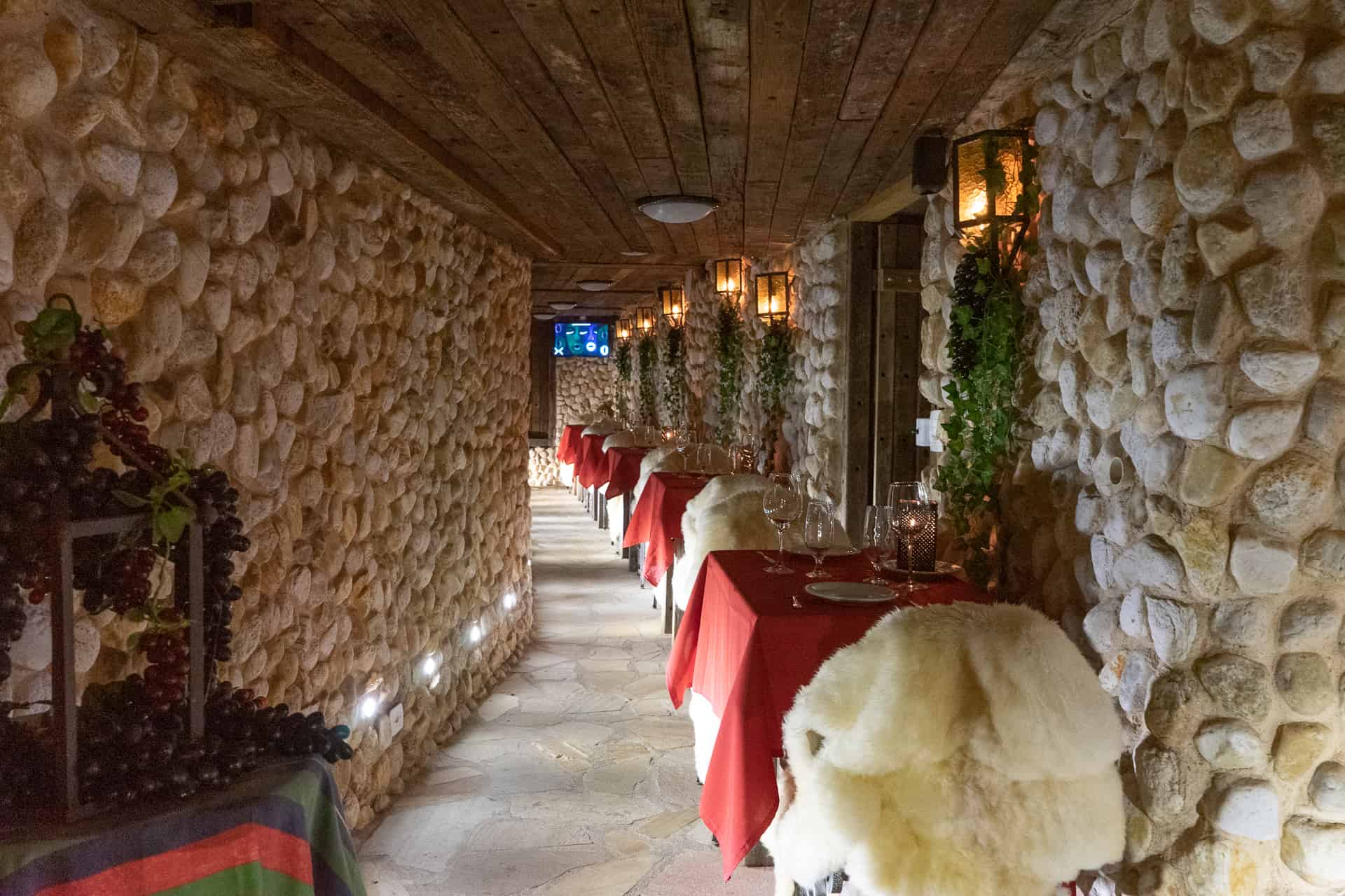 Entrada do restaurante com paredes de pedra e iluminação acolhedora